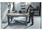 Mann in PARKSIDE PERFORMANCE® Arbeitshose bohrt in einer Werkstatt.