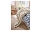 Weiche LIVARNO home Kuscheldecke auf einem Bett mit blau-weißer Bettwäsche.