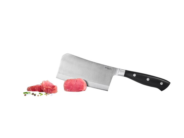 Fleischbeil mit rohen Fleischstücken und Gewürzen.