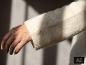 Nahaufnahme einer Hand und des Ärmels eines weißen ESMARA Mohair-Mix-Premium-Pullovers [KI-generiertes Bild]