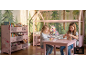 Zwei Mädchen spielen in einem rosa Kinderzimmer mit Hausbett und Spielzeugregal.