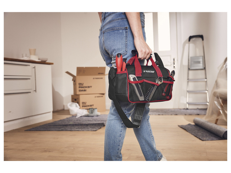Eine Person trägt eine Werkzeugtasche mit Parkside-Werkzeug während Renovierungsarbeiten.