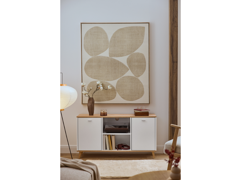 Eine weiße Kommode mit Holzplatte, dekoriert mit einem abstrakten Gemälde und einer Blumenvase.