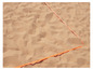 Eine orange Linie im Sand, wahrscheinlich für ein Volleyballfeld.