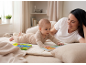 Mutter und Baby spielen auf dem Boden mit Babybüchern.
