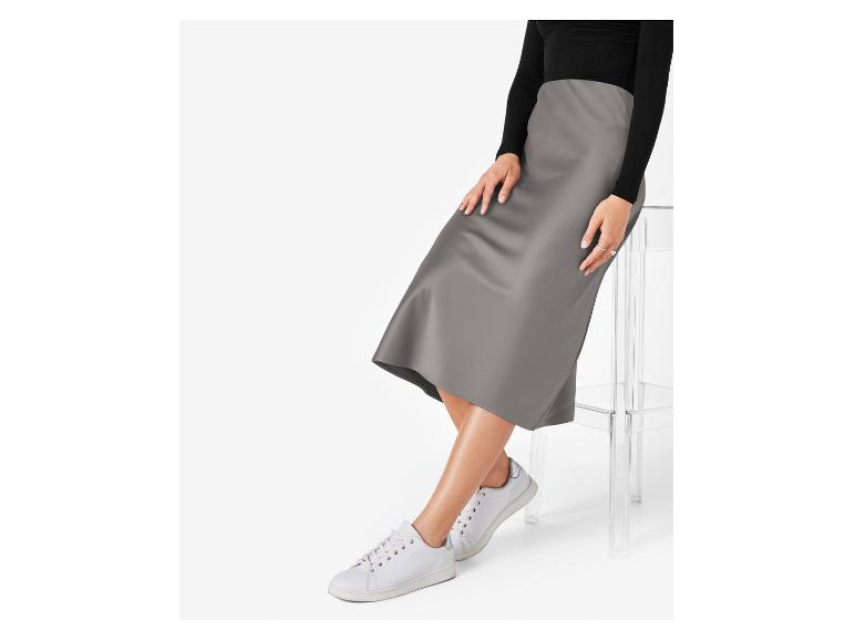 Eine Frau trägt einen grauen Satinrock und weiße Turnschuhe.