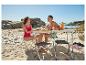 Paar genießt Strandpicknick mit Klapptisch, Klapphockern und frischem Obst.