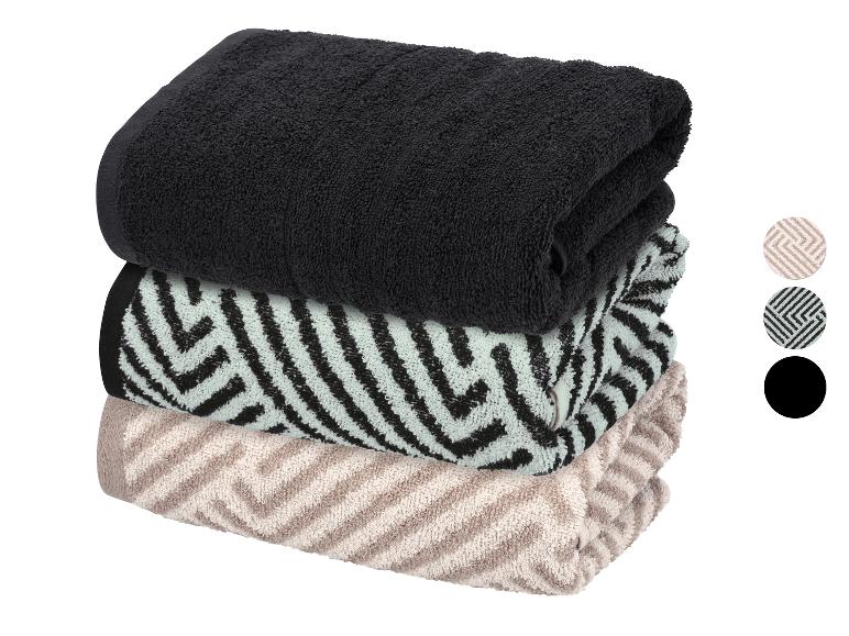 Stapel aus drei gefalteten Handtüchern: schwarz, hellgrün mit schwarzem Muster und beige mit Muster.