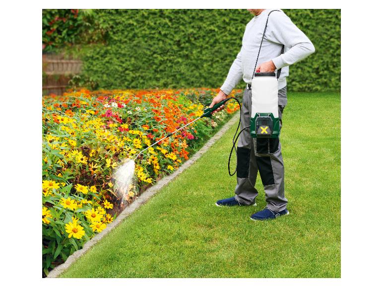 Mann besprüht Blumenbeet mit Handsprühgerät, Akku-Sprühgerät auf dem Rücken.