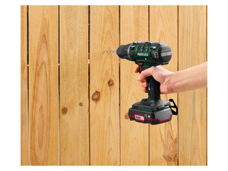 Eine Hand hält einen Parkside Akku-Bohrschrauber, der in einen Holzzaun bohrt.