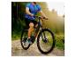 Mann fährt E-Mountainbike auf Waldweg bei Sonnenuntergang.