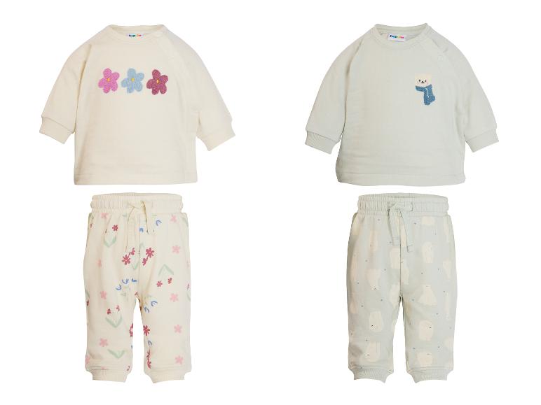 Zwei Baby-Outfits, eines mit Blumenmuster und eines mit Eisbärenmuster.
