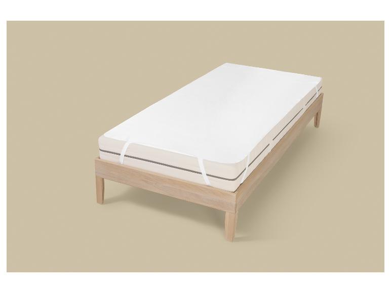 Einzelmatratze mit weißem Matratzenschoner auf hellem Holzlattenrost.