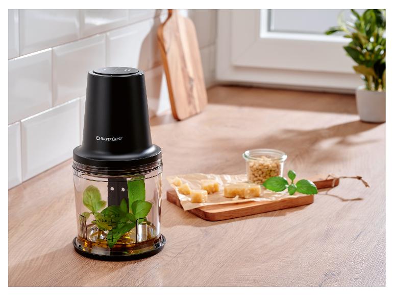 Schwarzer Silvercrest Zerkleinerer mit Basilikum und Öl, daneben Käse und Pinienkerne.