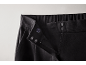 Nahaufnahme des Hosenbundes einer schwarzen Hose mit Reißverschluss, Knopf und Haken.