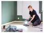 Frau justiert LIVARNO® Arbeitsleuchte „The Painter+“ in einem Raum mit gestrichenen Wänden.