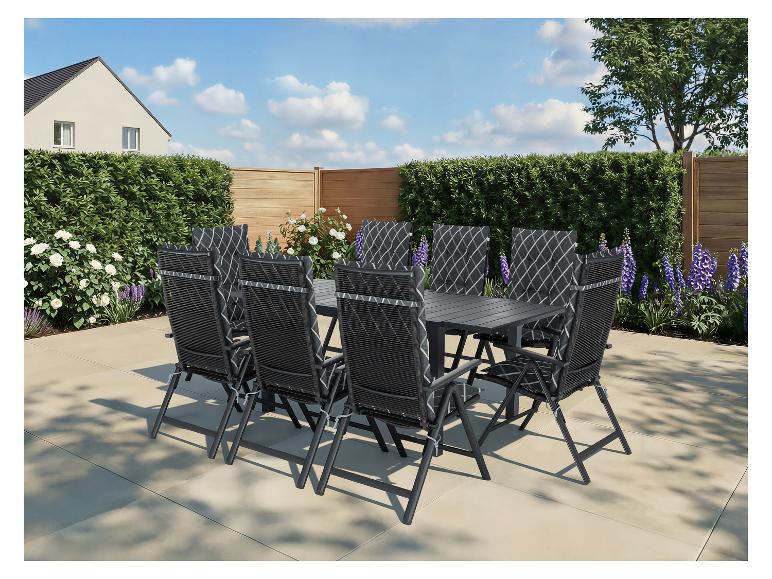 Gartenmöbel-Set mit schwarzem Tisch und Stühlen auf einer Terrasse, umgeben von Grün.
