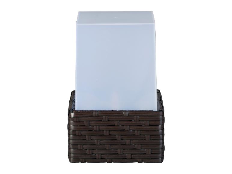 Eine weiße Lampe mit einem dunkelbraunen Rattansockel.