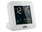 Weißer digitaler Wecker mit schwarzem Display, das die Uhrzeit 12:15 AM und den Alarm 7:00 AM anzeigt.