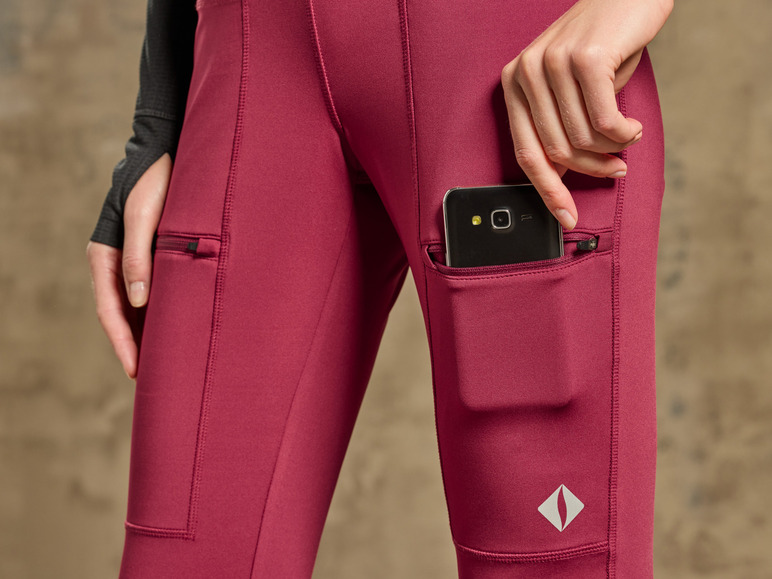 Eine Frau trägt rote Leggings mit einem Handy in der Tasche