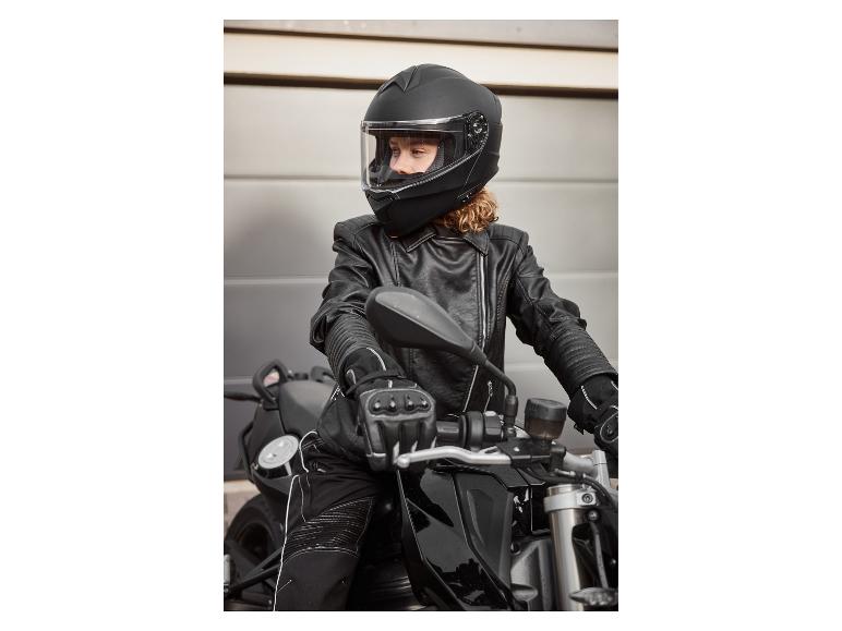 Frau in schwarzem Motorradhelm, Lederjacke und Handschuhen auf einem Motorrad