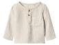 Cremefarbenes Langarm-Kinderoberteil mit Knöpfen und Tasche.