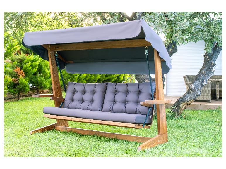Gartenschaukel aus Holz mit grauen Kissen und Dach auf grünem Rasen.