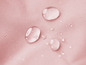 Wassertropfen auf rosa Stoff.