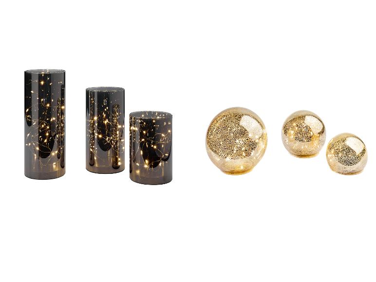 Drei zylindrische Vasen mit Lichtern und drei goldene Dekokugeln.
