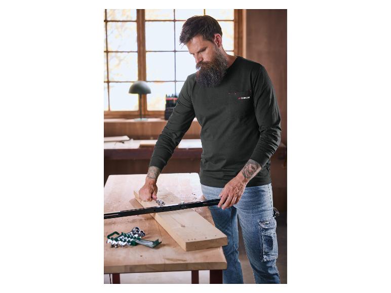 Bärtiger Mann in einem Parkside Langarmshirt und Jeans, der an einem Stück Holz arbeitet.