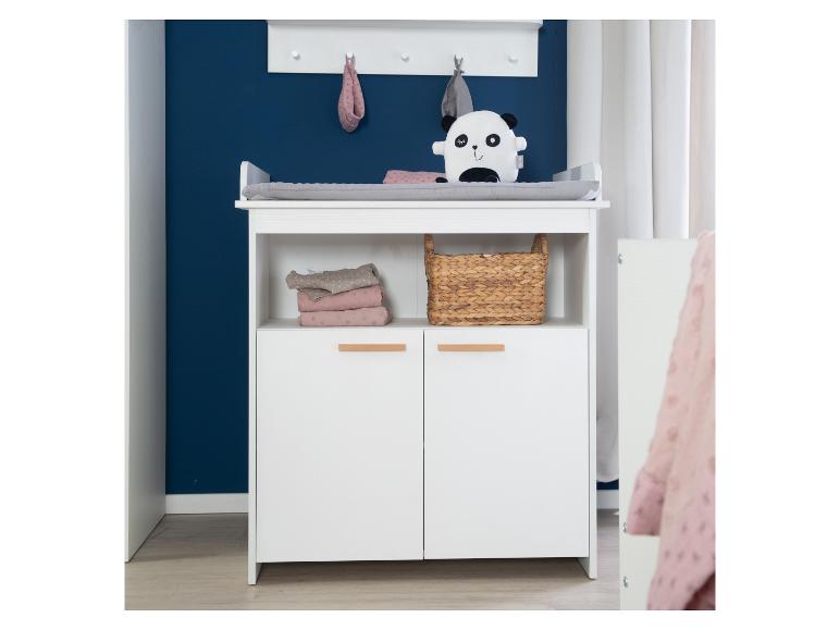 Weißer Wickeltisch mit offenen Regalen, Schränken und einem Panda-Plüschtier vor einer dunkelblauen Wand.