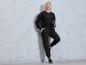 Model in einem schwarzen Pullover und Jogginghose mit Taschen