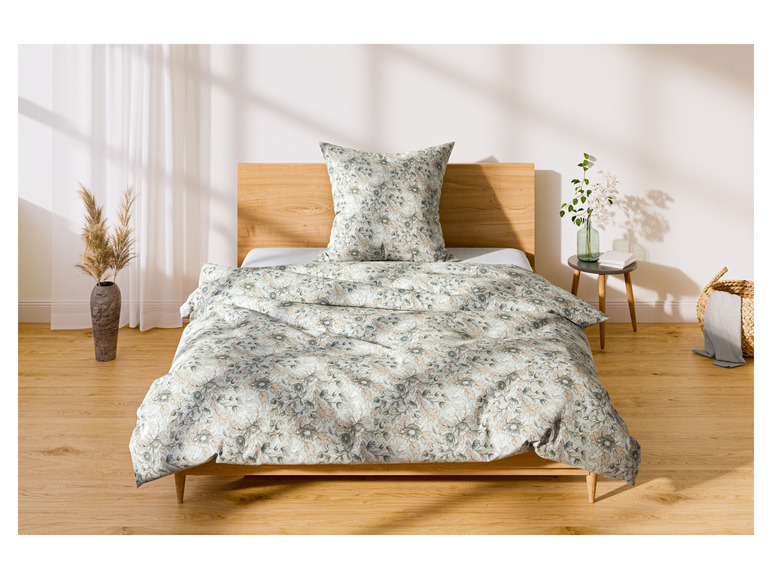 Ein Bett mit einer Bettdecke und einem Kissen mit Blumendruck.