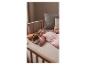 Baby schläft im Kinderbett in rosa Schlafsack mit leuchtendem Plüschtier.