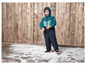 Ein Kind in einem blauen Winteroverall steht auf einem Holzboden mit künstlichem Schnee.