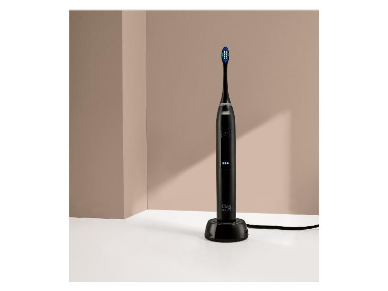 Eine schwarze elektrische Zahnbürste mit blauen Borsten und Anzeigelichtern, auf einer Ladestation.