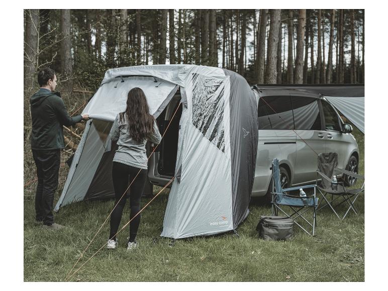Ein Easy Camp Zelt, ein Auto, Stühle und eine Kühlbox im Wald.