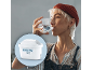 Frau trinkt Wasser mit einem Maxtra Pro Wasserfilter im Vordergrund.