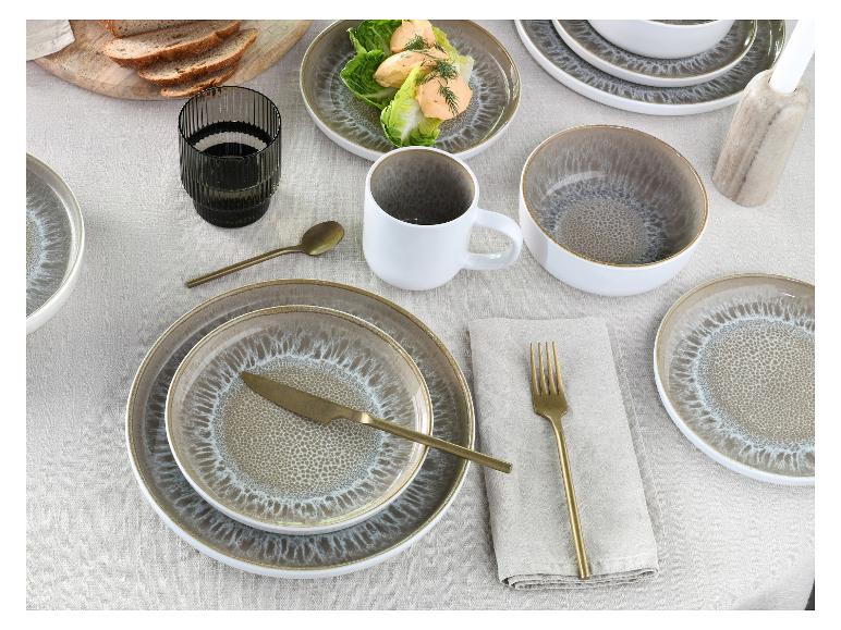 Tisch gedeckt mit Steingut-Tellern, Schalen und Tassen, mit goldenem Besteck und Brot.