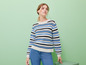 Eine Frau trägt einen gestreiften Pullover und blaue Jeans.