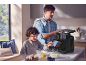 Vater und Sohn backen mit einer schwarzen Küchenmaschine, Zutaten auf dem Tisch.