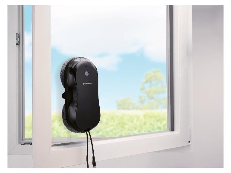 SilverCrest Fensterputzroboter an einem Fenster mit Blick ins Grüne.