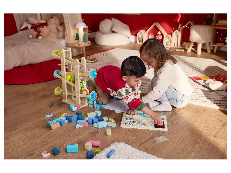 Zwei Kinder spielen auf dem Boden mit Holzspielzeug und einem Puzzle.