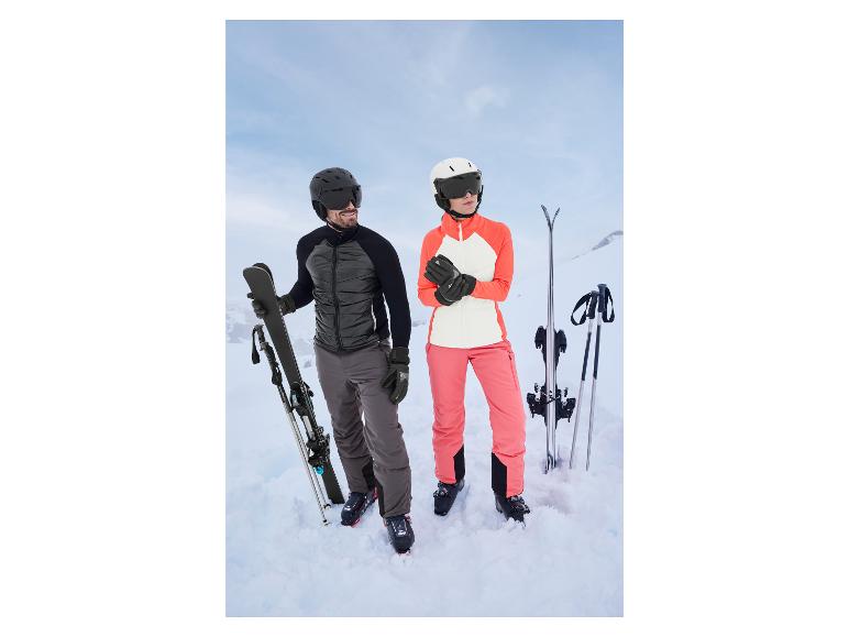 Ein Mann und eine Frau in Skikleidung stehen im Schnee mit Skiern und Stöcken.