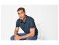 Mann in marineblauem Poloshirt und Jeans sitzt auf weißem Stuhl