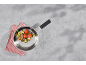 Pfanne mit gebratenen Tomaten, Zucchini und Pilzen auf grauem Untergrund.