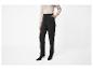 Frau in beigem Pullover und schwarzer High-Waist-Hose, mit Hand in der Tasche.