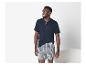 Mann in dunkelblauem kurzärmeligem Henley-Shirt und karierten Boxershorts.