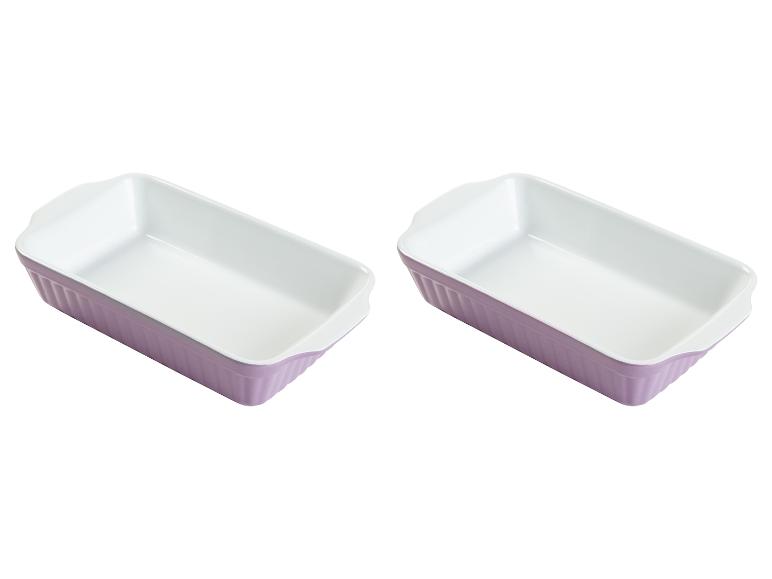 Zwei lilafarbene Backformen mit weißem Innenraum.