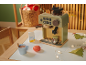Spielzeug-Kaffeemaschine mit Zubehör, einer Tasse heißer Schokolade und Weihnachtsdekoration.